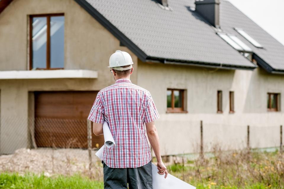 Conducteur de travaux avec les plans devant une maison en construction